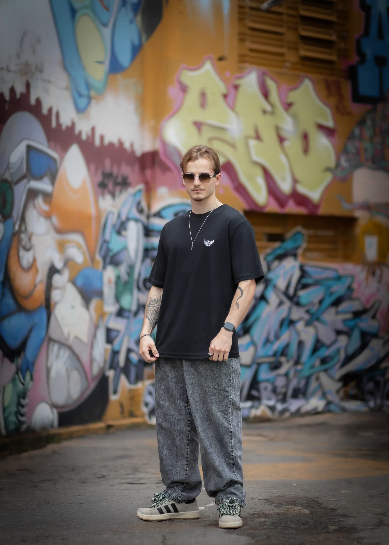 Modelo de camiseta preta da KOUNTING em beco grafitado